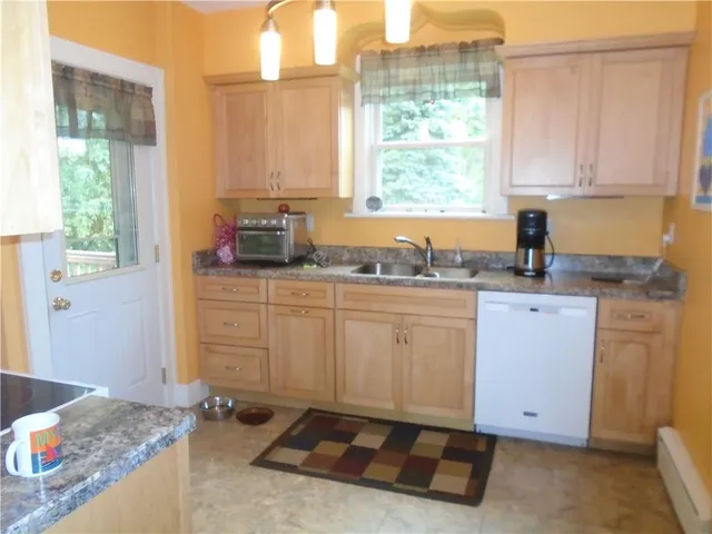 a kitchen with granite countertop a sink window and cabinets