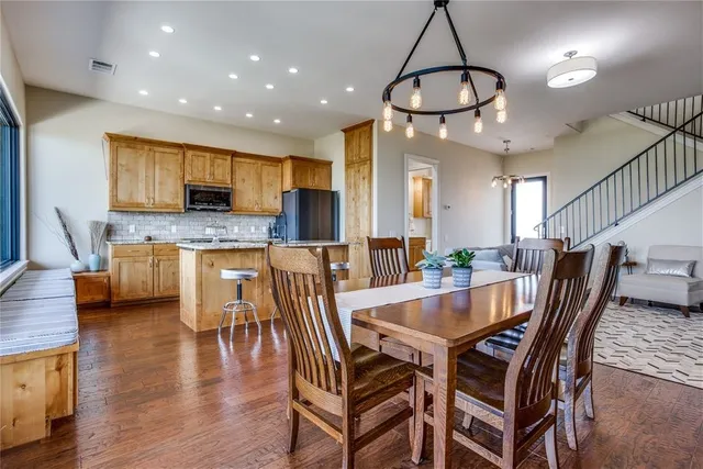 a dining room with stainless steel appliances kitchen island granite countertop a dining table chairs and a refrigerator