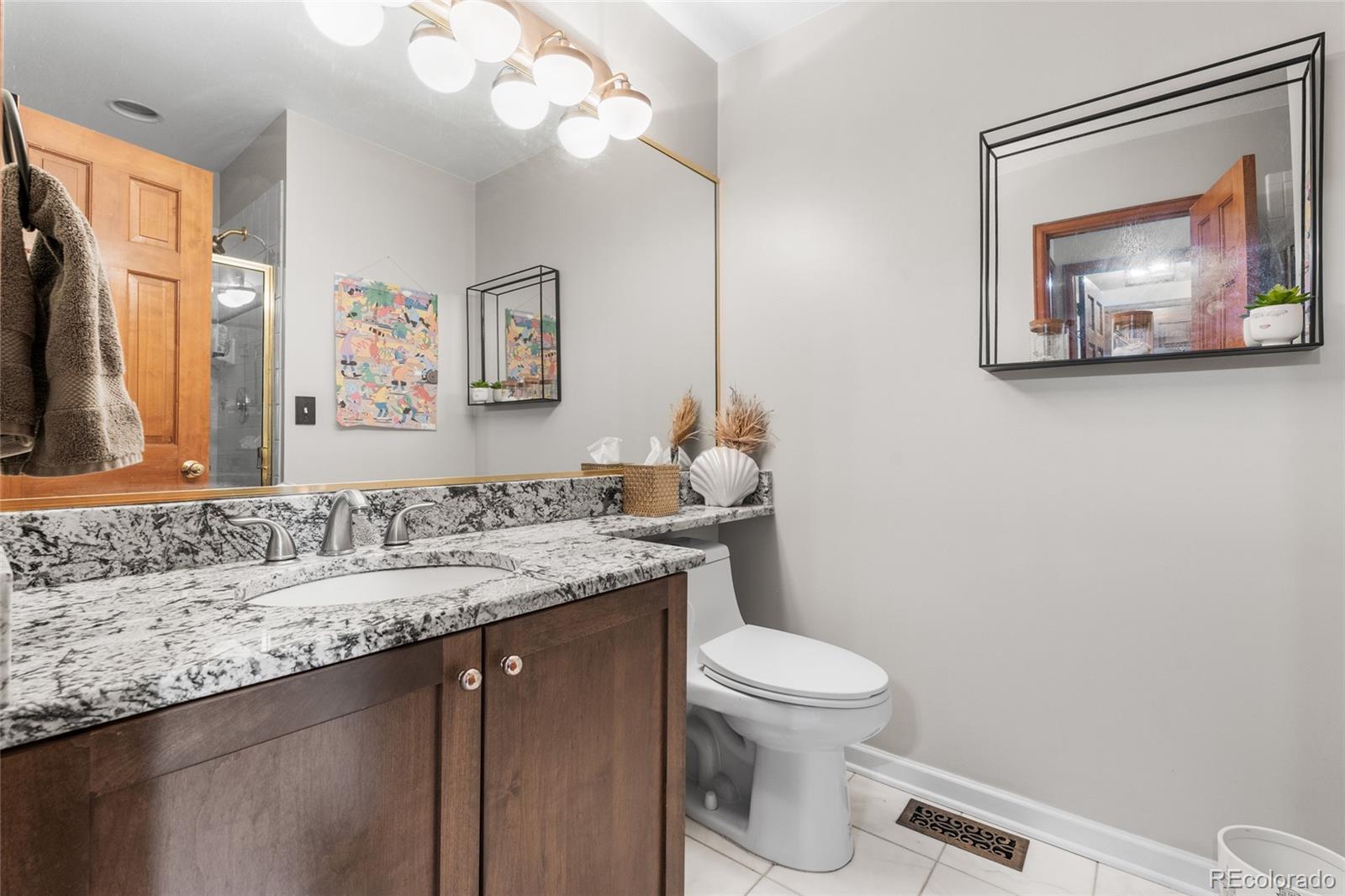 4852 South Carson Street Aurora, CO 80015 - Photo 28 of 50 a bathroom with a granite countertop sink mirror vanity and toilet