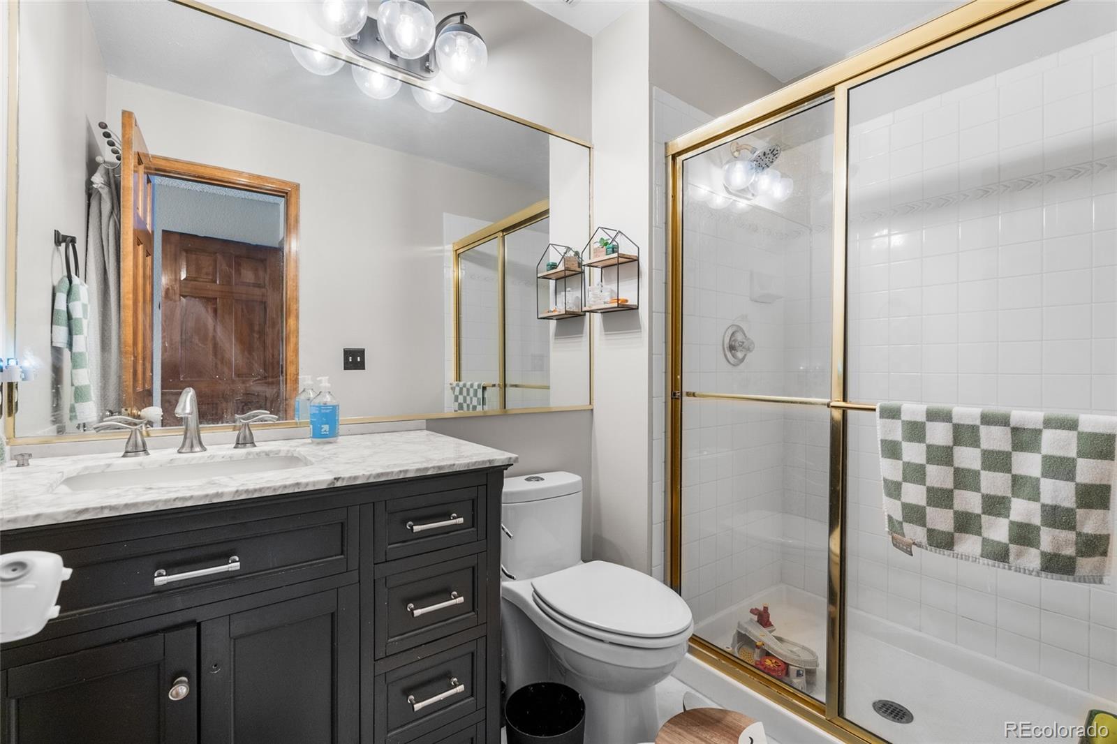 4852 South Carson Street Aurora, CO 80015 - Photo 44 of 50 a bathroom with a granite countertop sink toilet mirror and shower