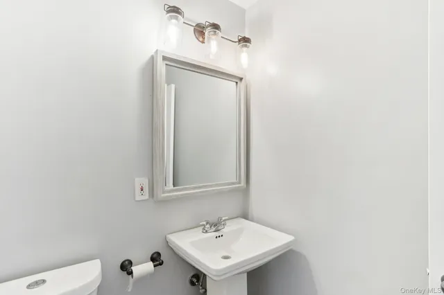 a bathroom with a sink a toilet and a mirror