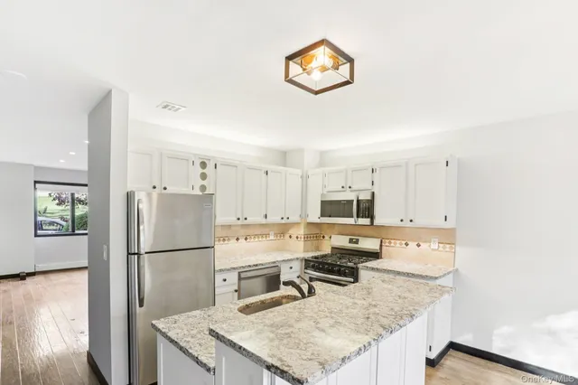 a kitchen with stainless steel appliances granite countertop a refrigerator a stove top oven a sink and dishwasher