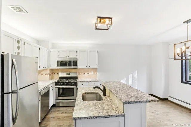 a kitchen with granite countertop a sink stove and refrigerator