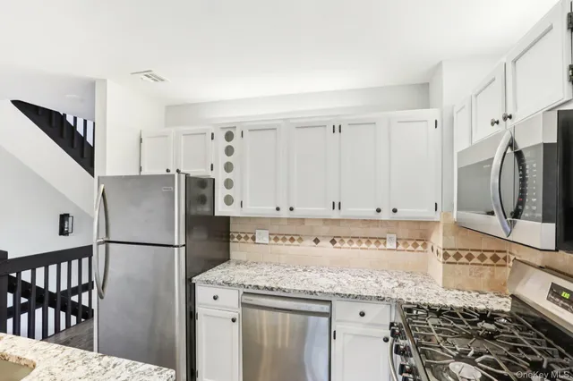 a kitchen with stainless steel appliances granite countertop a refrigerator a stove and a sink