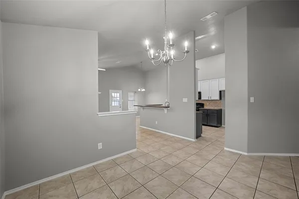 a view of a hallway with kitchen and chandelier