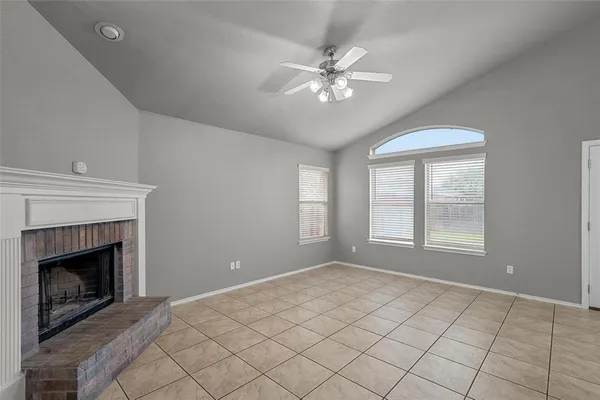 a view of an empty room with chandelier fan and fire fireplace