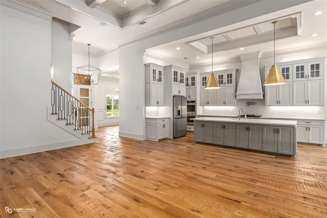 a view of a kitchen with kitchen island stainless steel appliances wooden floor and a sink