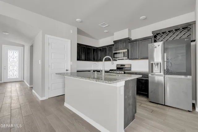 a kitchen with stainless steel appliances granite countertop a refrigerator sink and cabinets