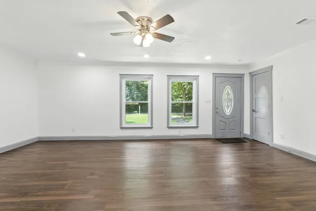 a view of an empty room with wooden floor and a window