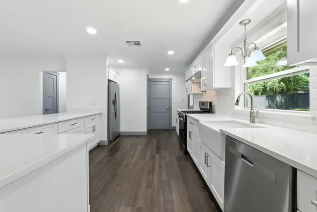 a kitchen with granite countertop white cabinets and refrigerator