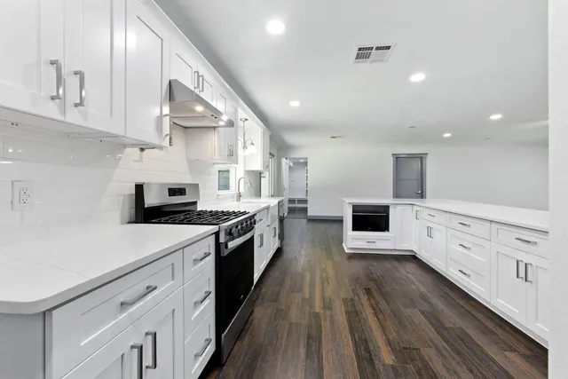 a kitchen with white cabinets and sink