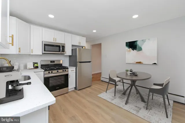 a kitchen with stainless steel appliances a stove a sink a microwave a refrigerator a dining table and chairs