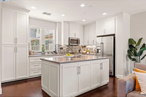 a kitchen with white cabinets and refrigerator