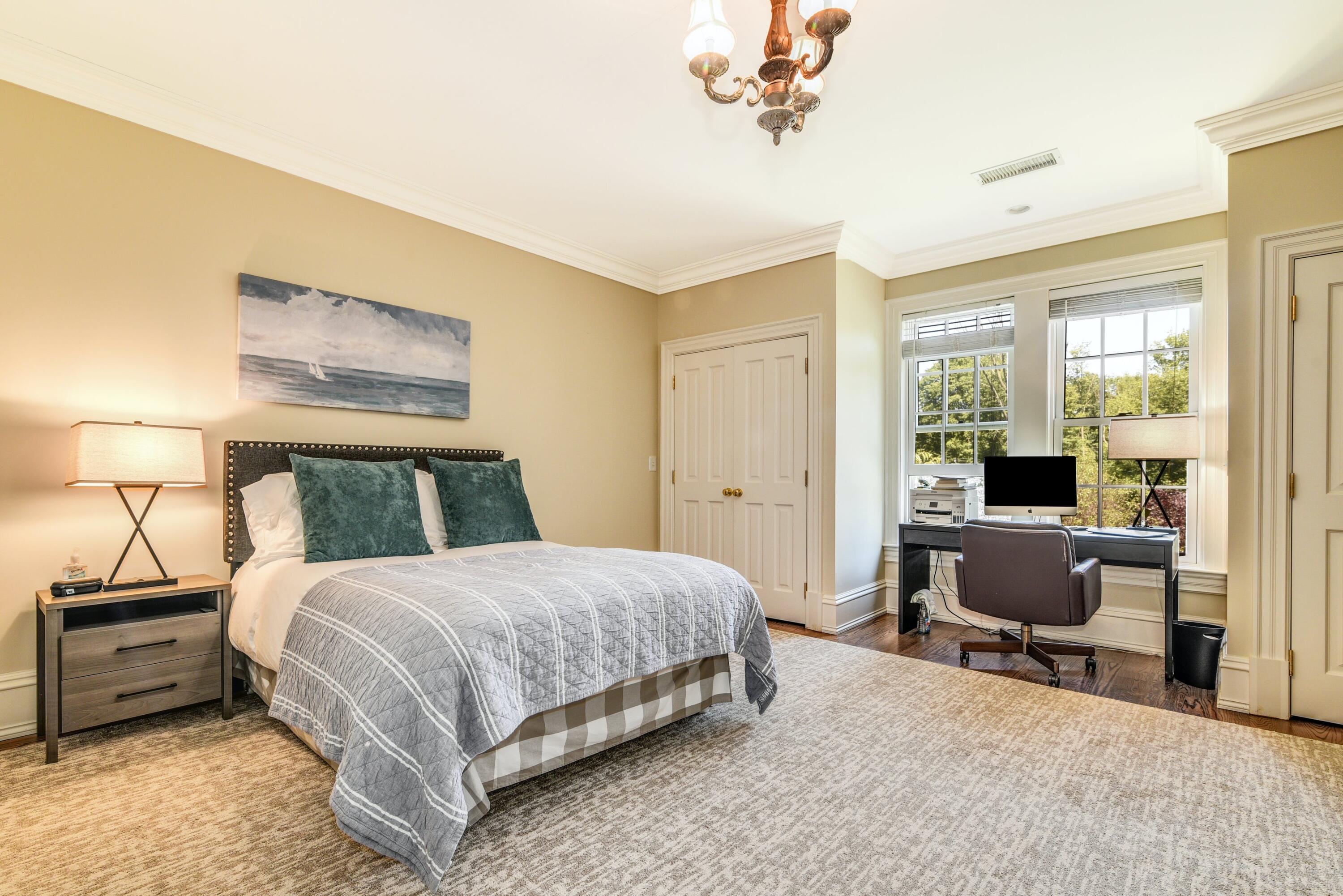 910 Smith Ridge Road New Canaan, CT 06840 - Photo 25 of 40 a bedroom with a bed and a chandelier