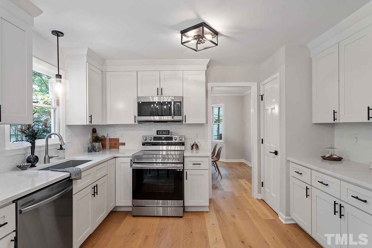 8805 Wellsley Way Raleigh, NC 27613 - Photo 4 of 39 a kitchen with stainless steel appliances white cabinets a sink a stove a refrigerator and microwave