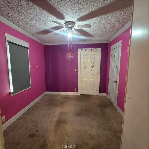 an empty room with windows and fan