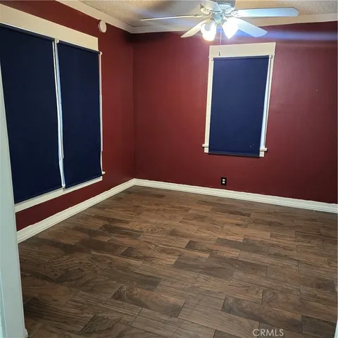 a view of an empty room with window and wooden floor