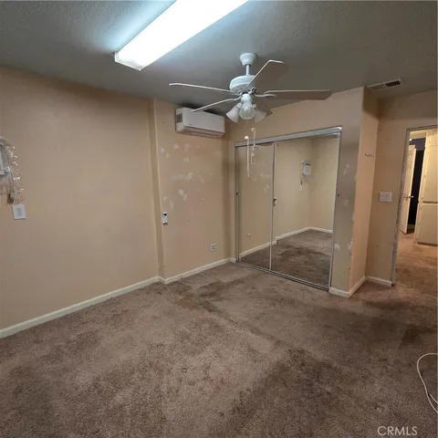 an empty room with closet and a chandelier fan
