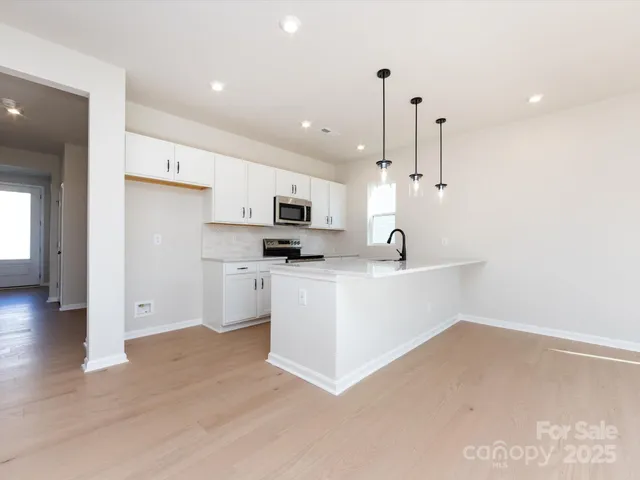 a view of kitchen with stainless steel appliances refrigerator oven and cabinets