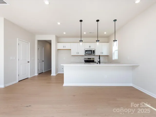 a view of kitchen with stainless steel appliances kitchen island sink refrigerator and window