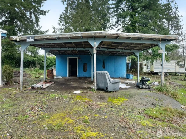 a view of backyard with table and chairs under an umbrella with a large tree