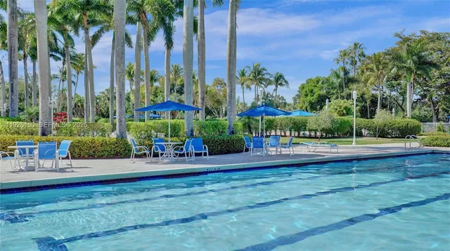 a view of a swimming pool with a yard and palm trees