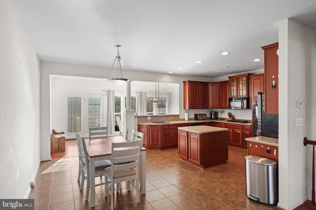 a kitchen with stainless steel appliances granite countertop a refrigerator a sink dishwasher a stove and a dining table with wooden floor