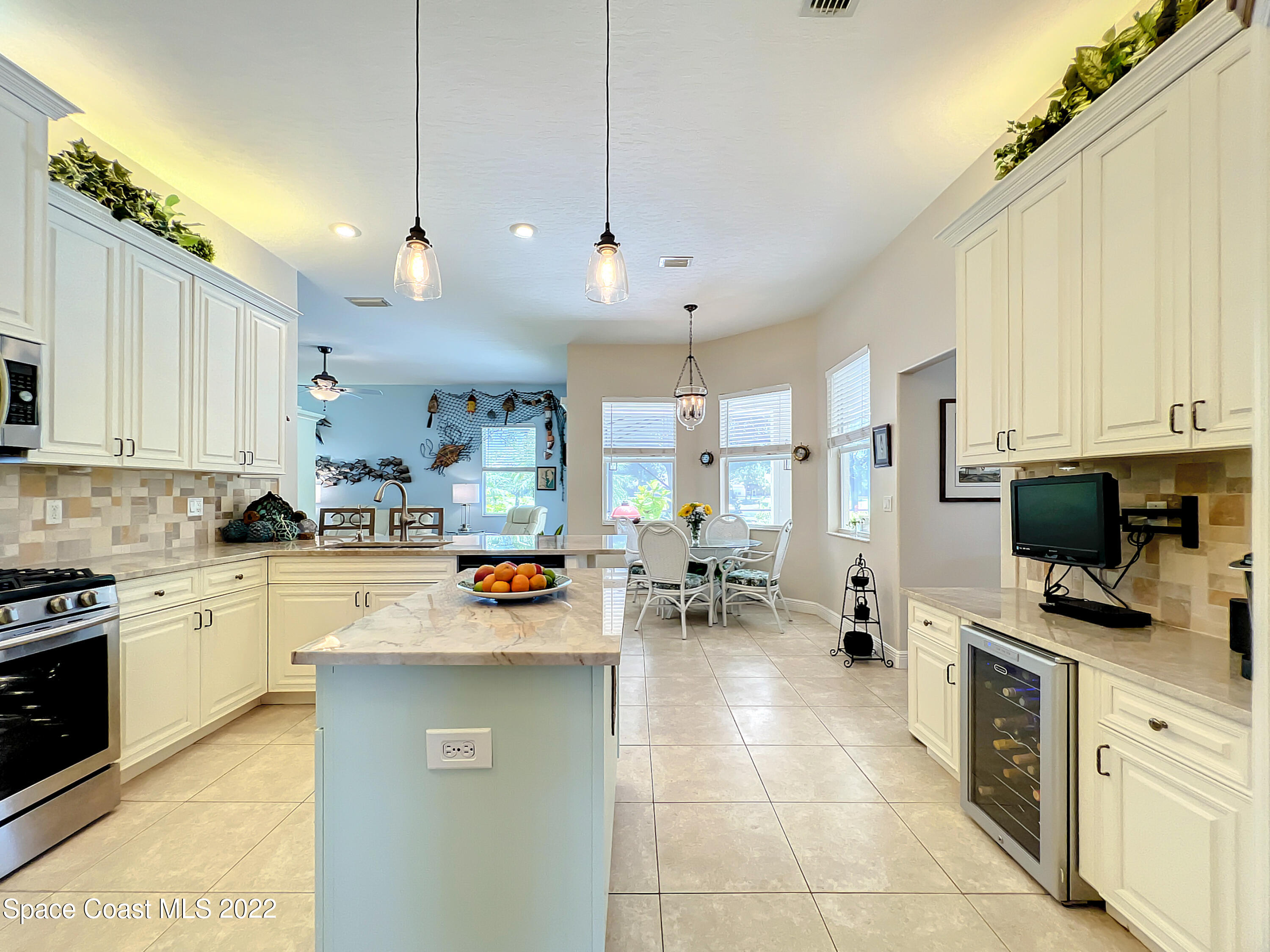 1705 Winding Ridge Circle Southeast Palm Bay, FL 32909 - Photo 9 of 45 a kitchen with stainless steel appliances kitchen island granite countertop a stove top oven a sink a dining table and chairs with white cabinets