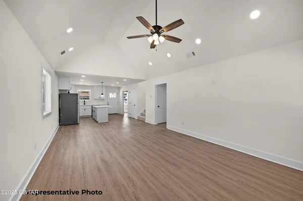 a view of an empty room with a window and wooden floor