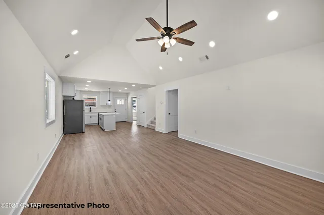 a view of an empty room with a window and wooden floor