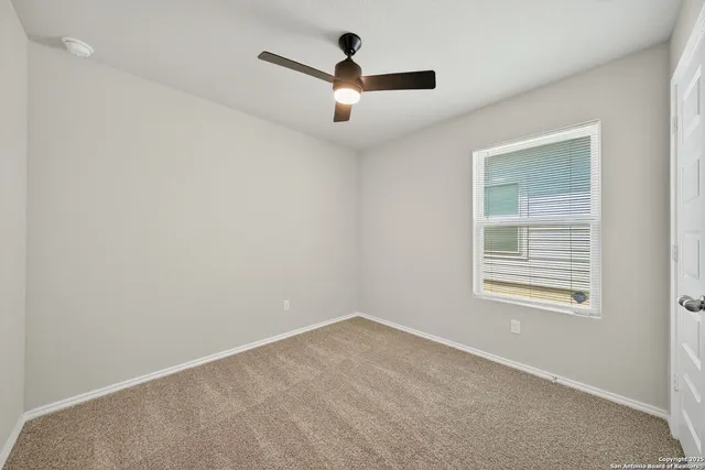 an empty room with ceiling fan and window