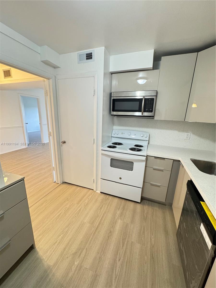 4160 Inverrary Drive, Unit 510 Lauderhill, FL 33319 - Photo 2 of 25 a kitchen with stainless steel appliances a stove a microwave and a hard wood floor