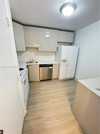 a view of a kitchen with refrigerator stove and wooden cabinets