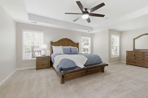 a spacious bedroom with a bed a chandelier and a large window