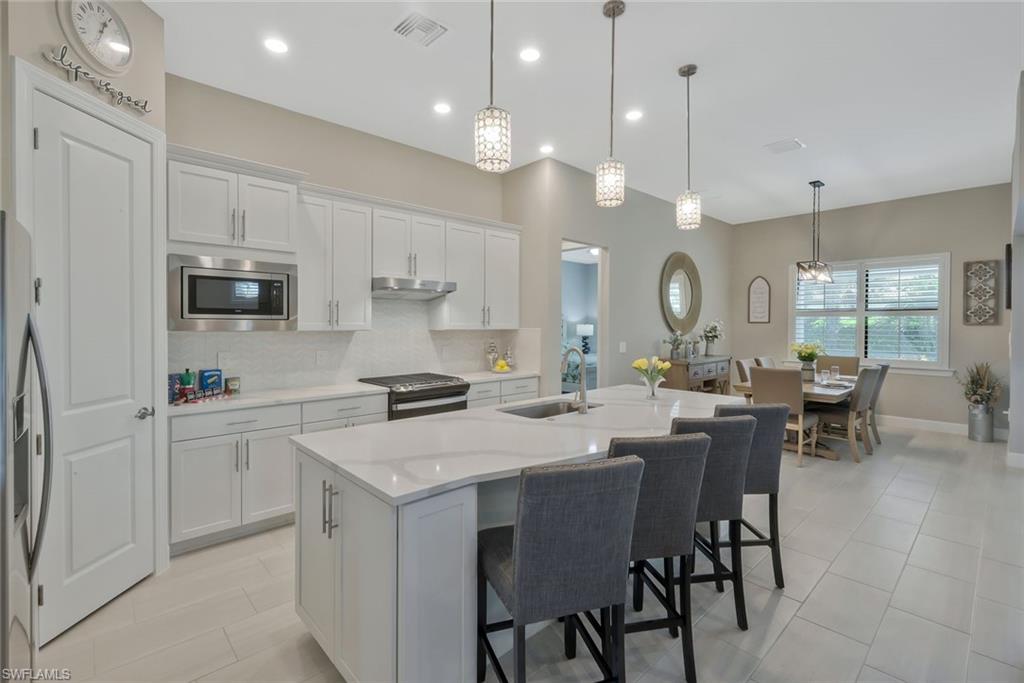 9640 Everglades Boulevard North Naples, FL 34120 - Photo 2 of 49 a kitchen that has a lot of cabinets in it with a dining table and chairs