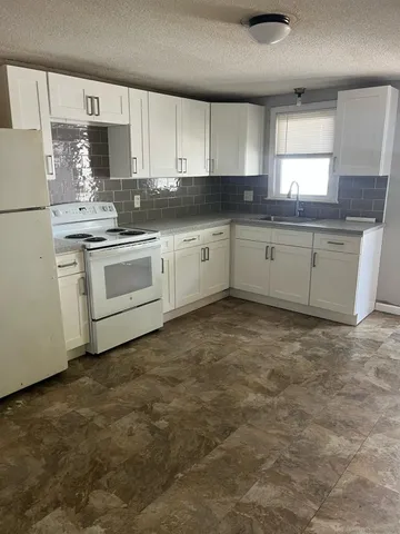 a kitchen with granite countertop a sink cabinets stainless steel appliances and a window