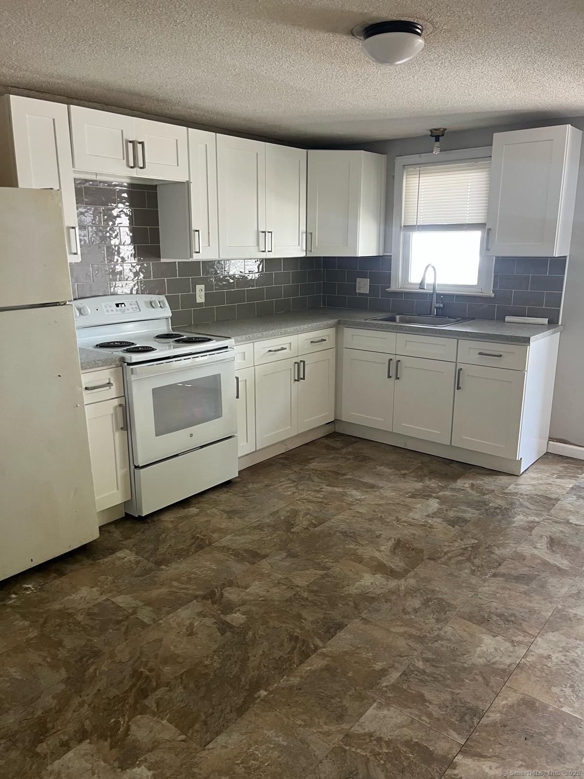 a kitchen with granite countertop a sink cabinets stainless steel appliances and a window