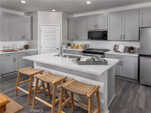 a kitchen with a stove a sink and white cabinets
