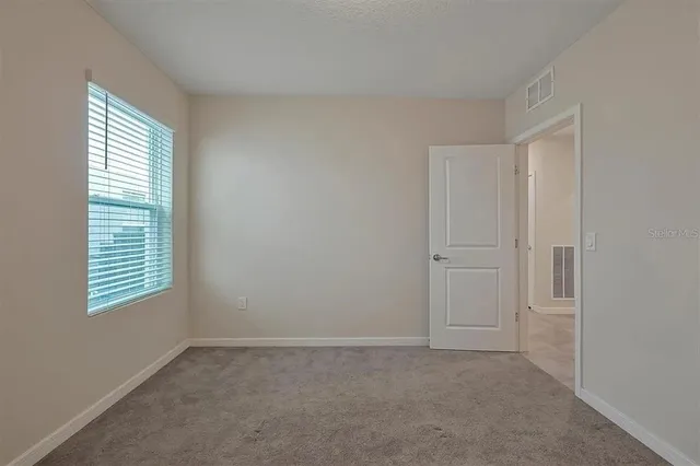 a view of an empty room with a window and closet area