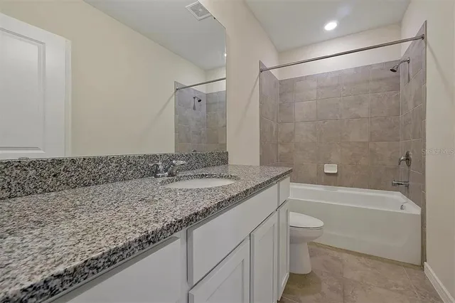 a bathroom with a granite countertop sink a toilet and bathtub