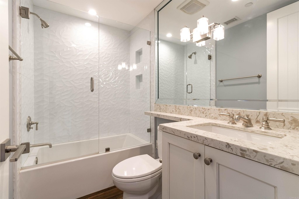 728 Silver Street La Jolla, CA 92037 - Photo 23 of 44 a bathroom with a granite countertop sink a toilet a mirror a bathtub and shower