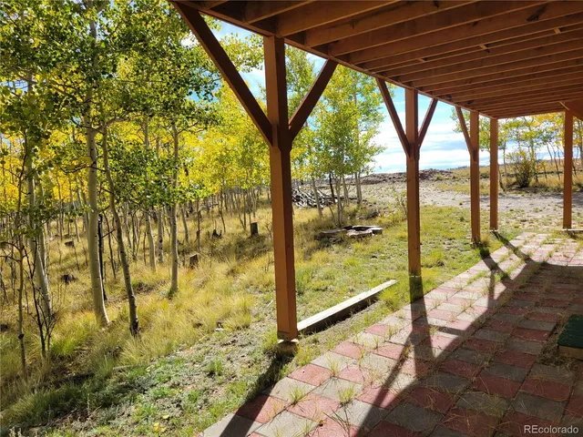 a backyard of a house with large trees and outdoor seating