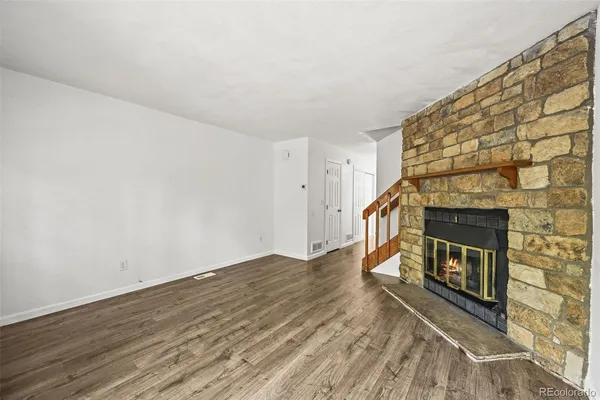 a view of an empty room with wooden floor and a fireplace