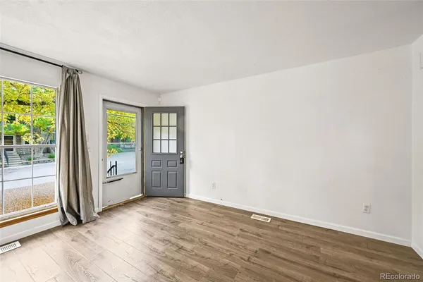 an empty room with wooden floor and windows