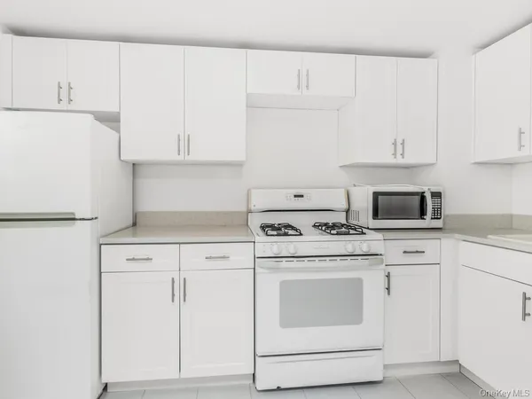 a kitchen with white cabinets and white appliances