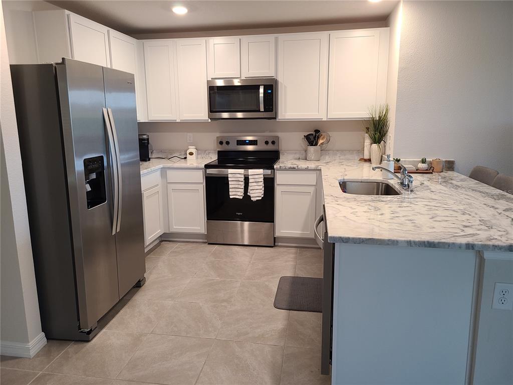 10209 Kalamazoo Place Parrish, FL 34219 - Photo 4 of 25 a kitchen with stainless steel appliances granite countertop a refrigerator stove a sink and a microwave