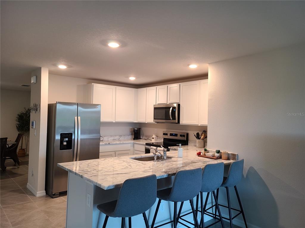 10209 Kalamazoo Place Parrish, FL 34219 - Photo 5 of 25 a kitchen with stainless steel appliances granite countertop a sink a stove a refrigerator with a dining table and chairs