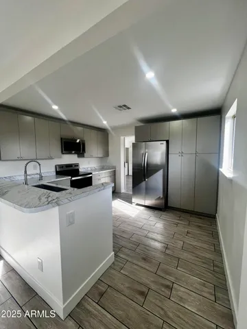 a kitchen with stainless steel appliances granite countertop a sink a stove and a refrigerator