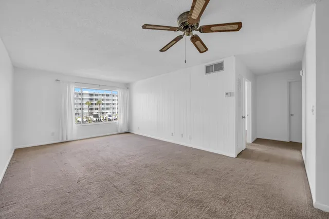 an empty room with windows and fan