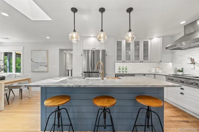 a kitchen with stainless steel appliances granite countertop a table chairs sink and stove top oven